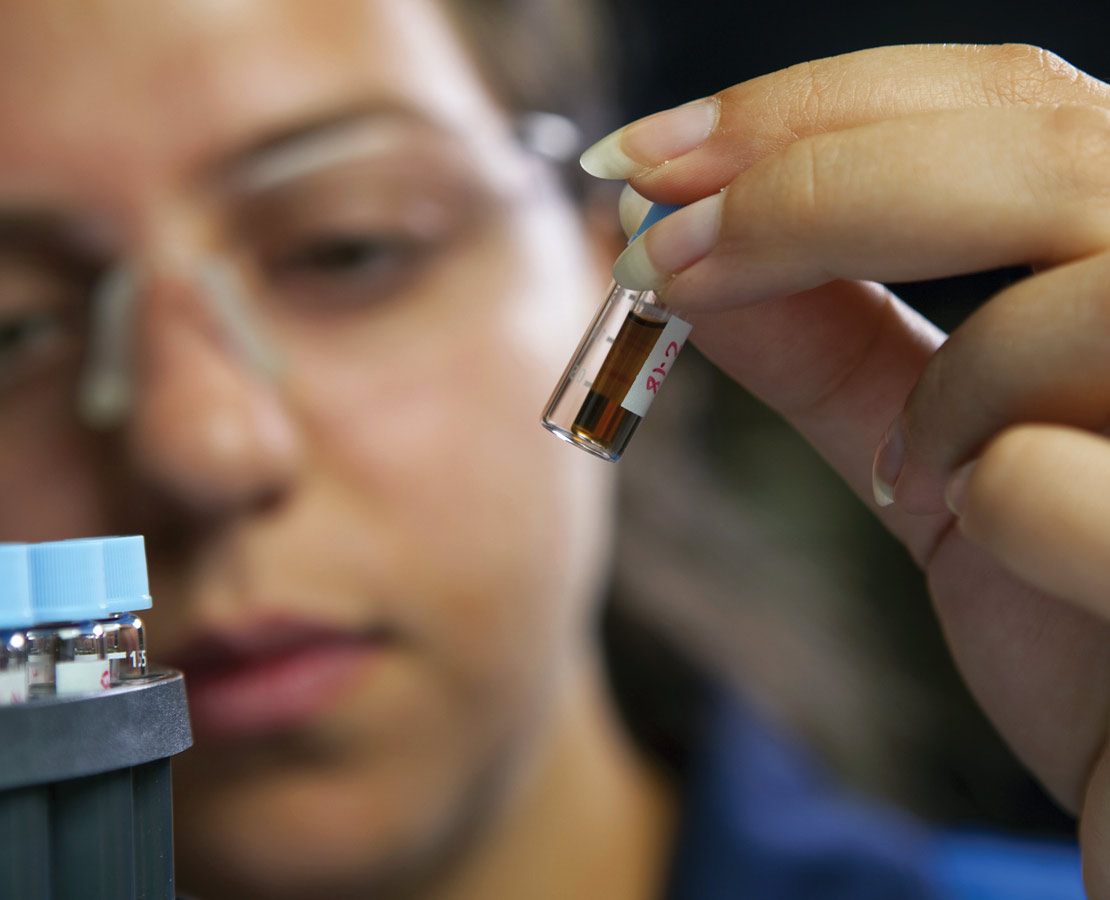 Schlumberger lab worker looking at sample.