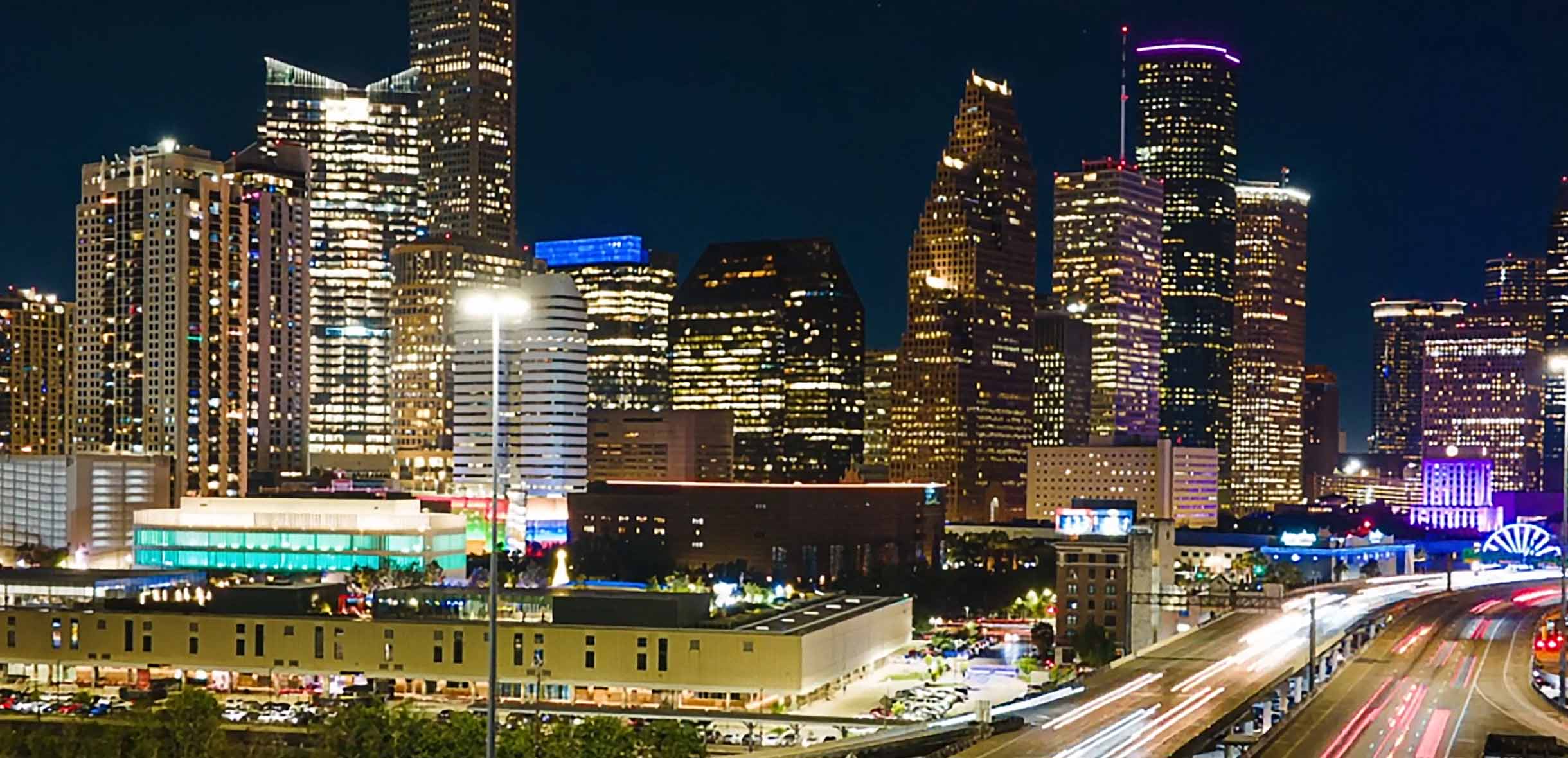 A photo of downtown Houston at night, showing illuminated skyscrapers.