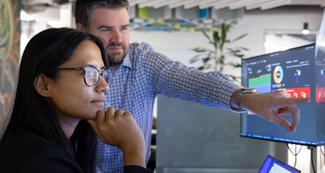Two SLB employees analyzing data on a computer screen
