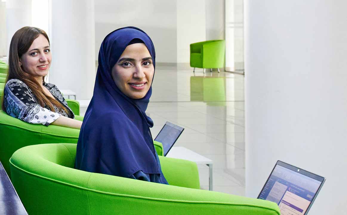 Two female employees sitting in chairs holding laptops