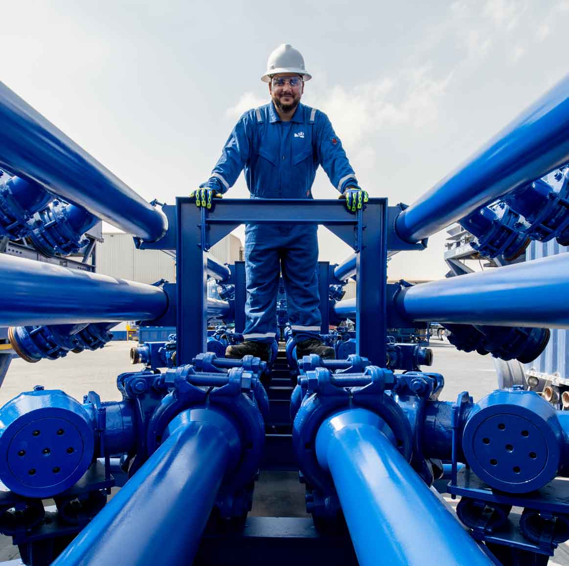Male operator standing in front of blue equipment and piping