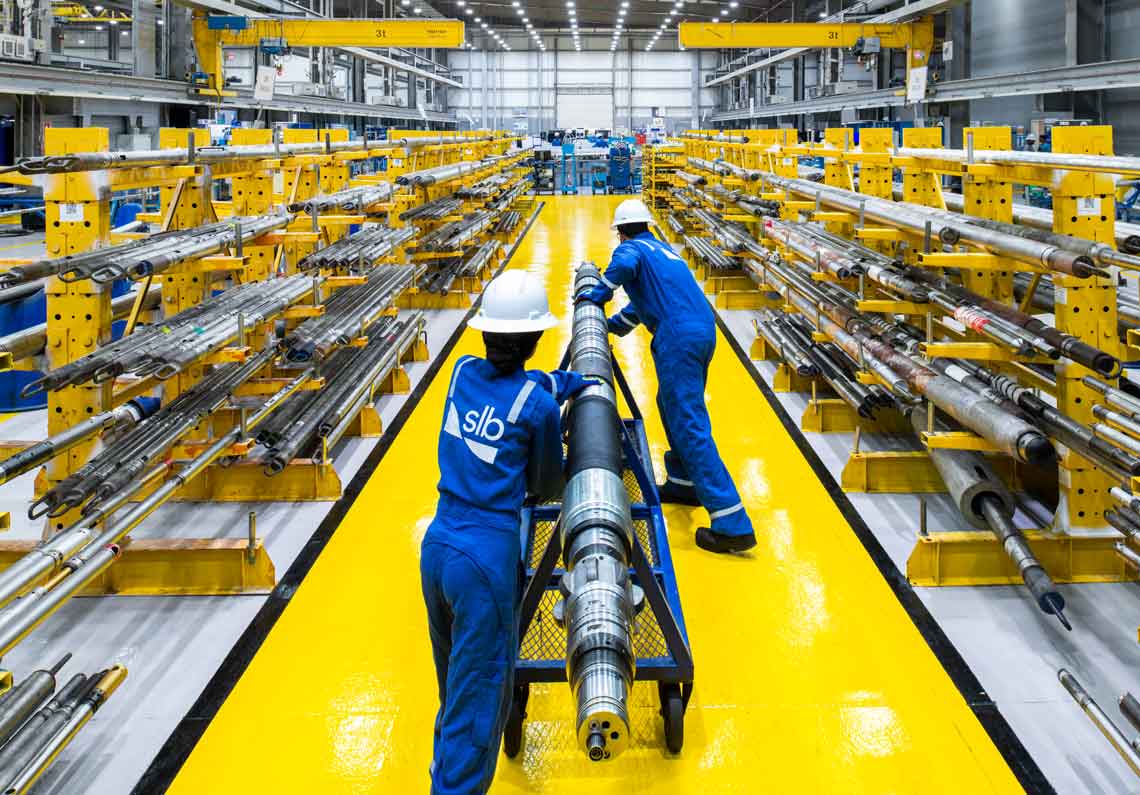 Two operators moving a piece of equipment down a manufacturing facility hallway