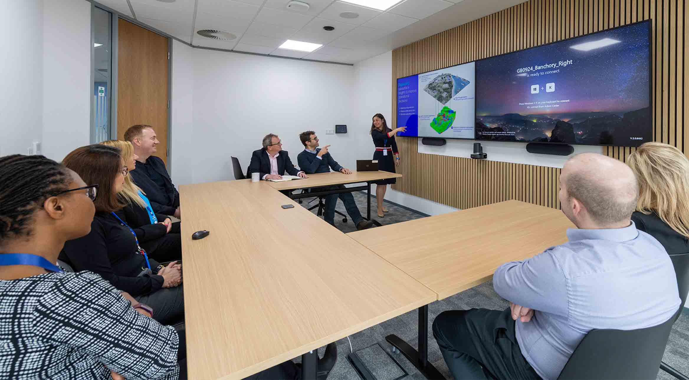 Photo of group of people in a meeting room, discussing presentation