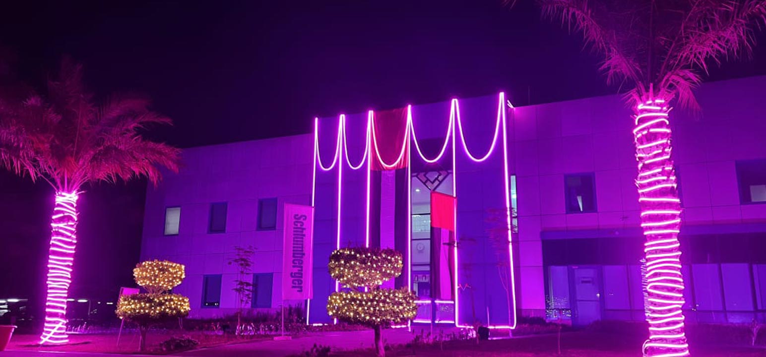 The front face of a Schlumberger building lit up with purple-colored lighting in support of International Day of Persons with Disabilities