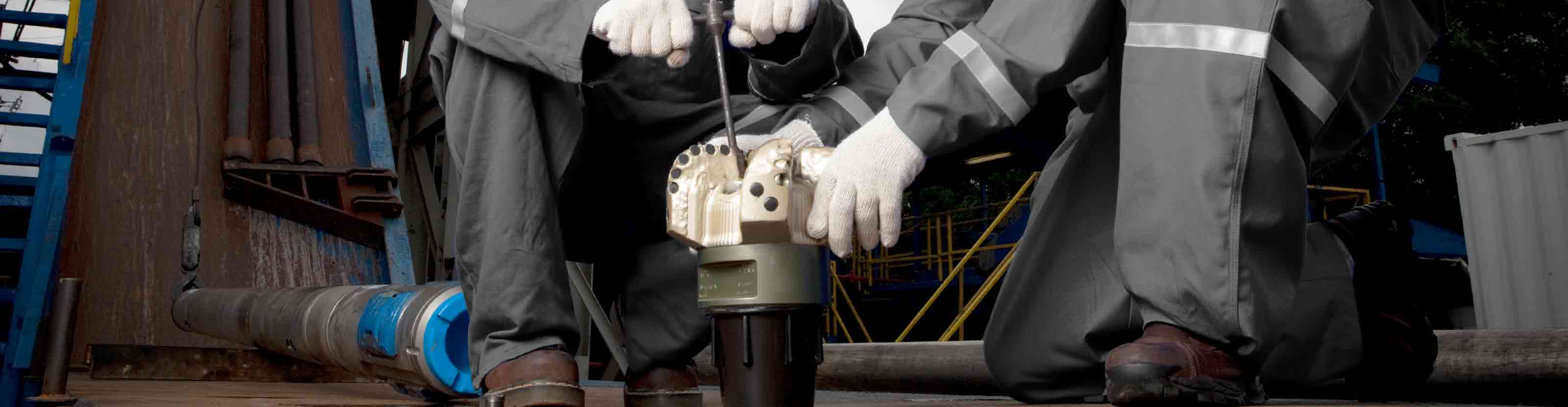 Drillers checking PDC bit nozzles on rig floor 