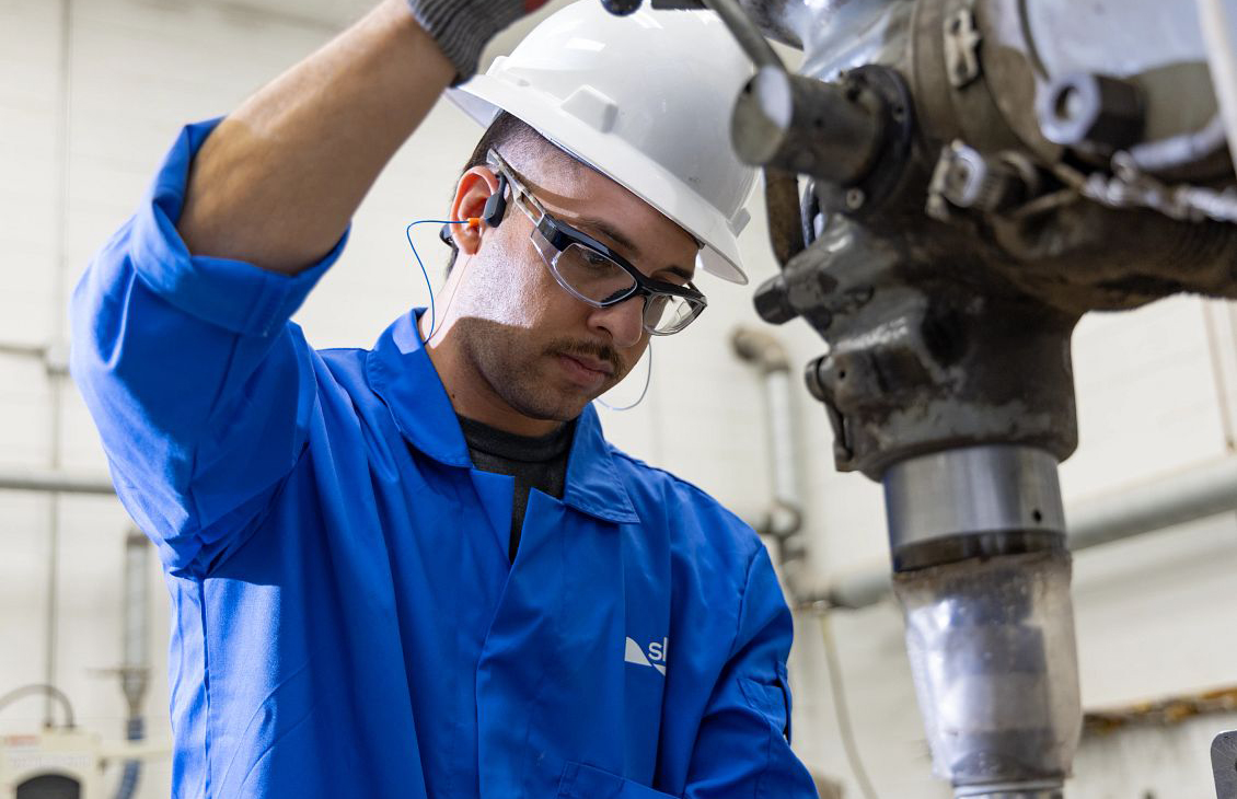 man in blue overalls and white hard hat using drill