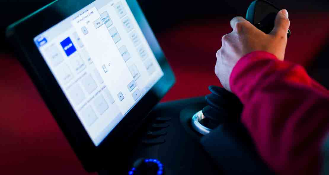 Close-up of an operators hand on the joystick of the x-com chair