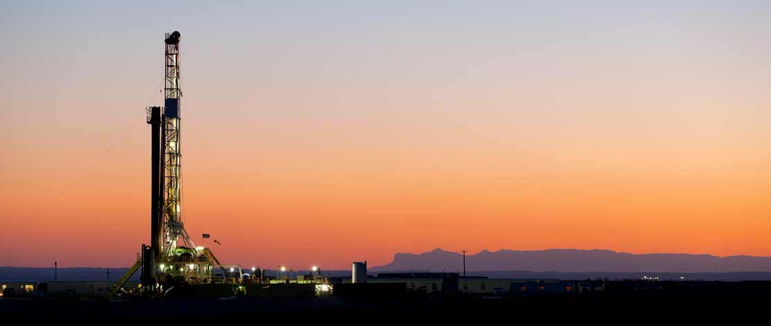 Drilling rig with a sunset and mountain backdrop