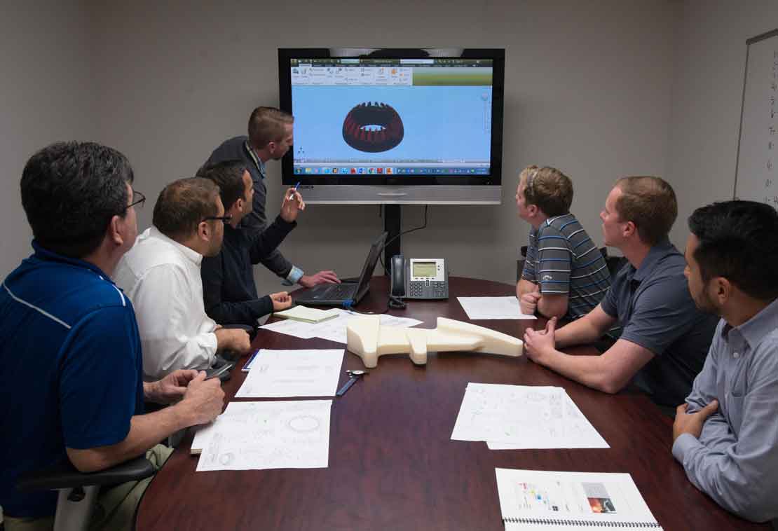 Men around table looking at a screen.