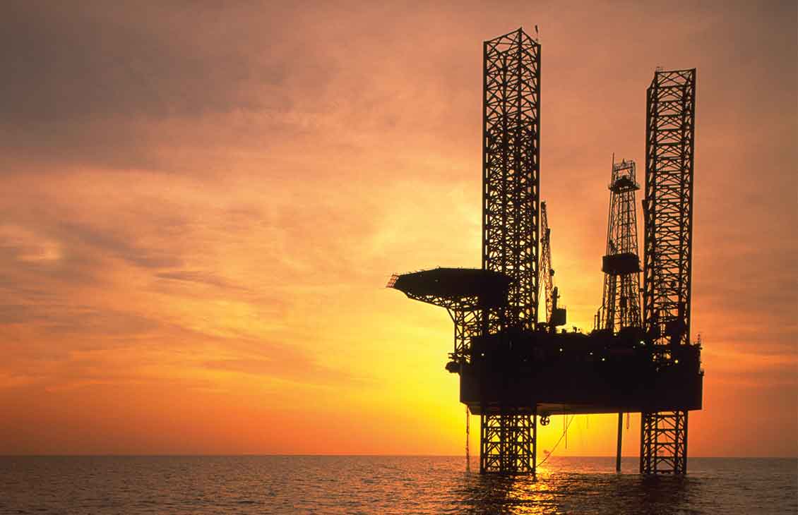 Rig in ocean with sunset in the background