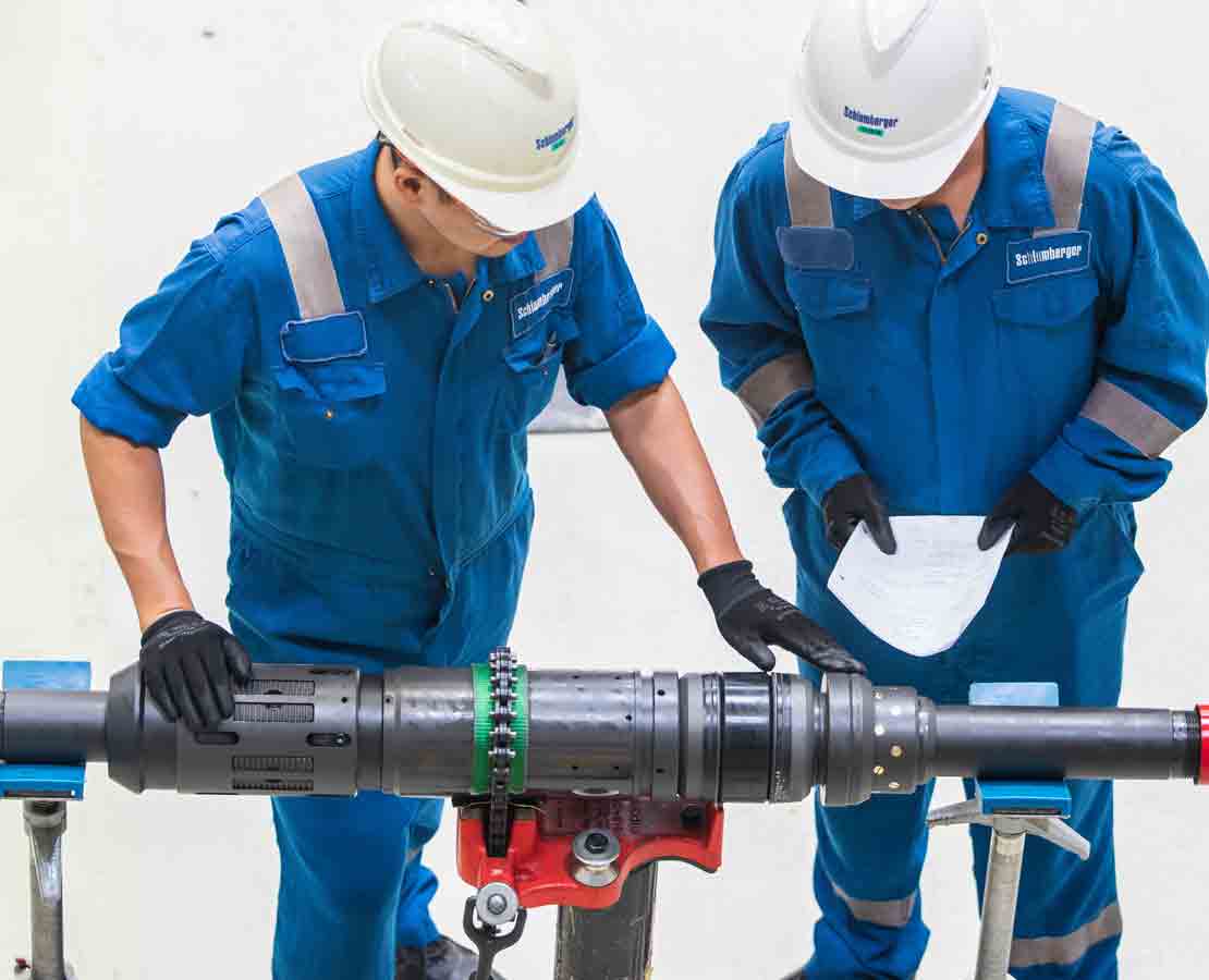 Two Schlumberger Workers Inspecting an MRP Conventional Modular Packer