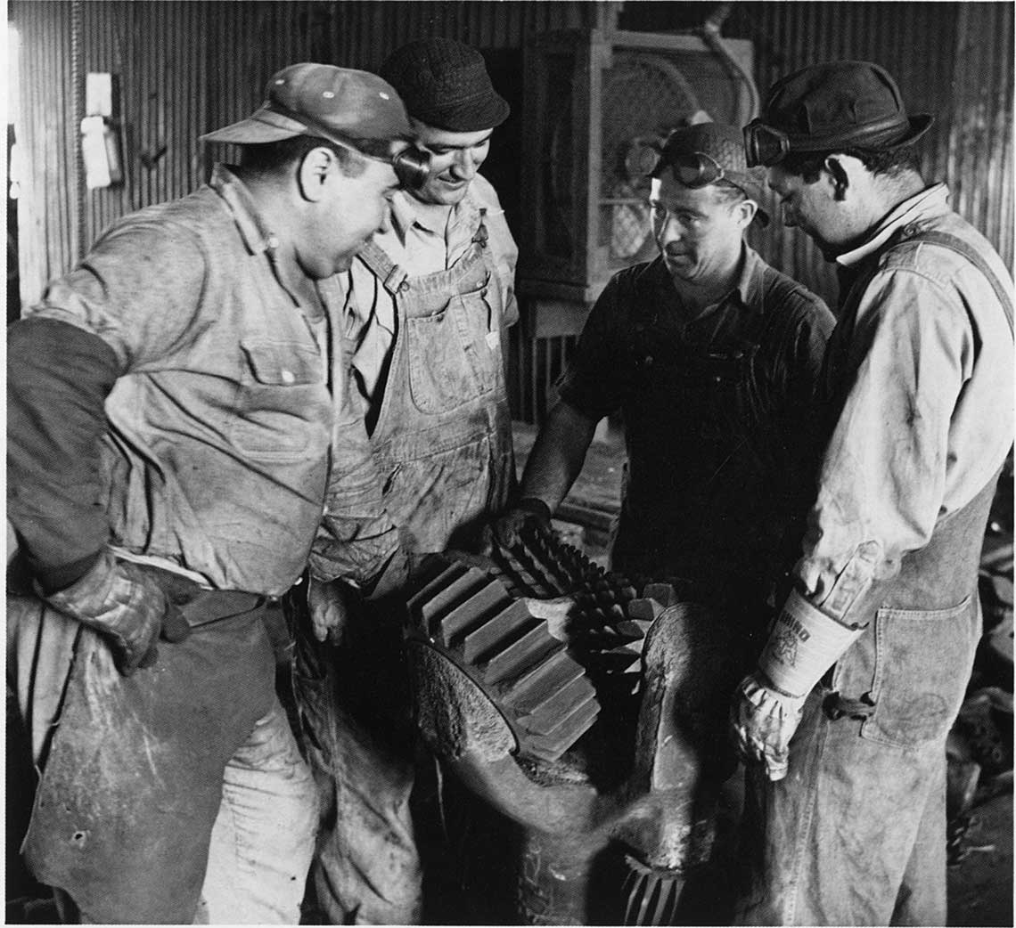 Smith’s commitment to quality is clear as craftsmen rigorously inspect a 24-in 4-point rock bit, a practice that built the foundation for modern drilling success (early 1950s).
