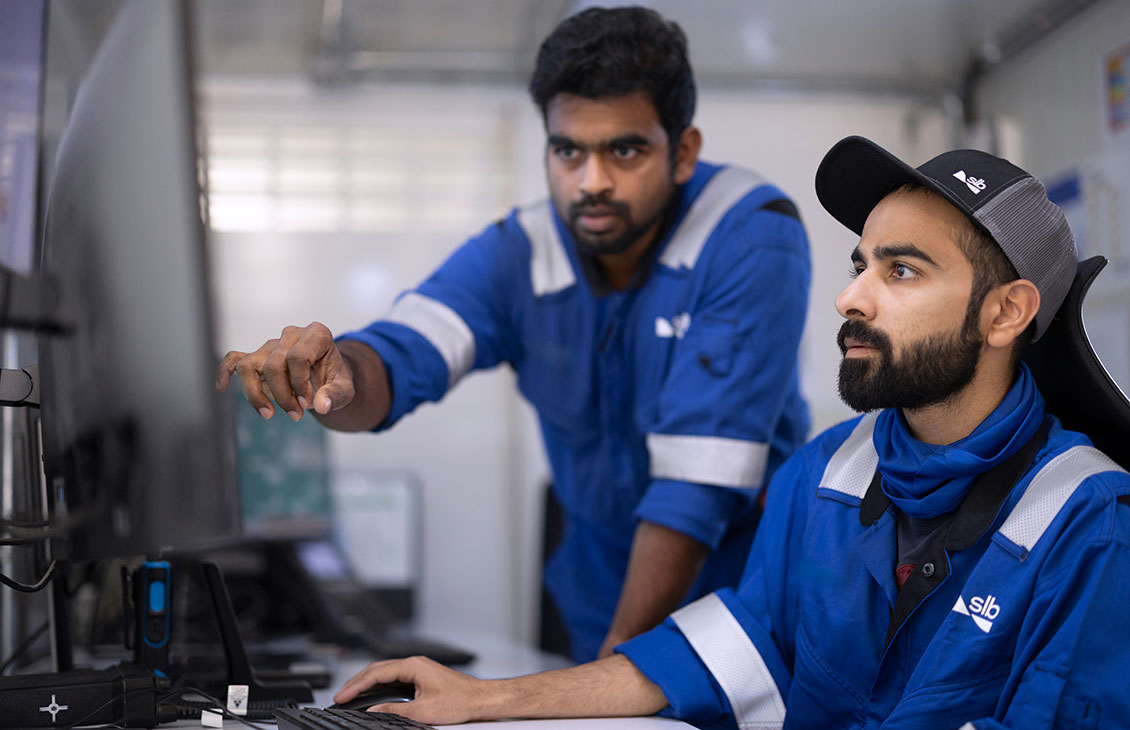 Two SLB field workers conferring in front of a computer screen