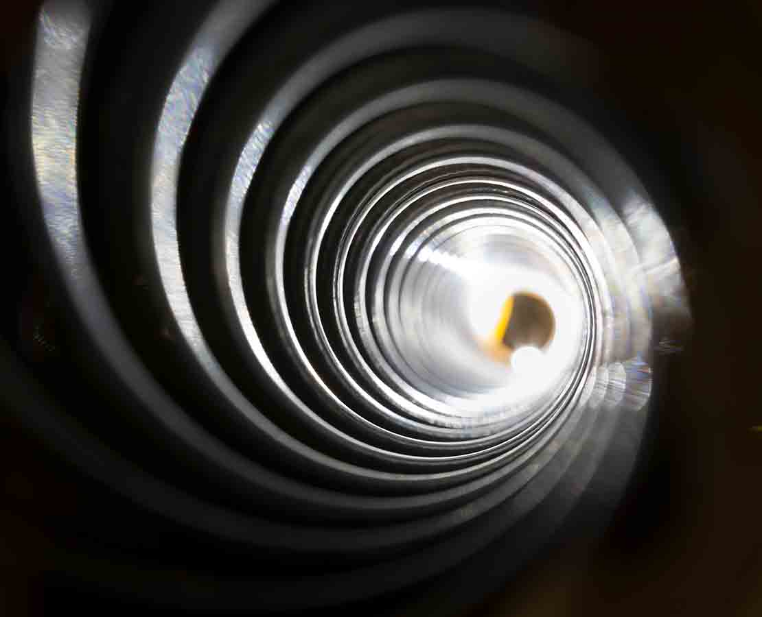 Looking down the dark spiral of the inside of a drilling motor stator to a bright light at the end