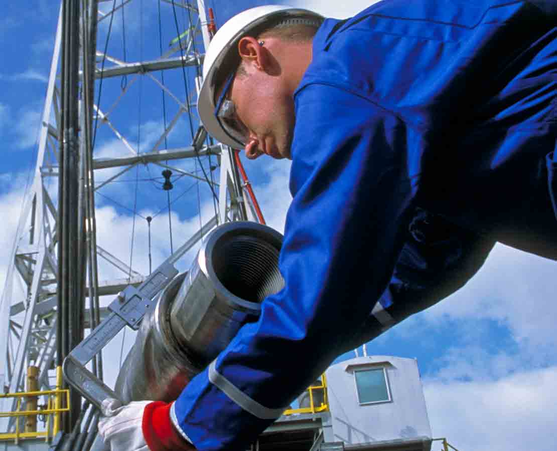 A Schlumberger field technician at a rigsite verifies specifications on a PowerDrive vorteX RSS