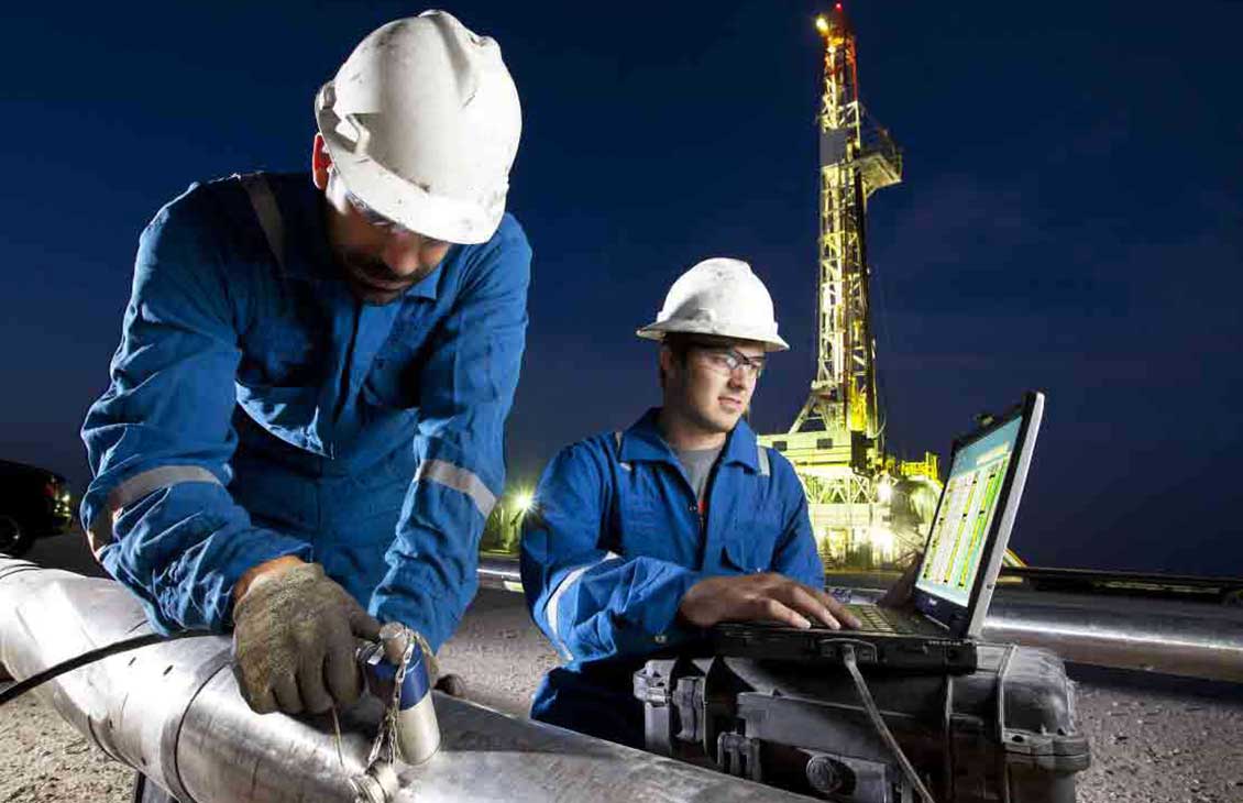 SLB technicians configuring an LWD tool on a drilling pad at night.