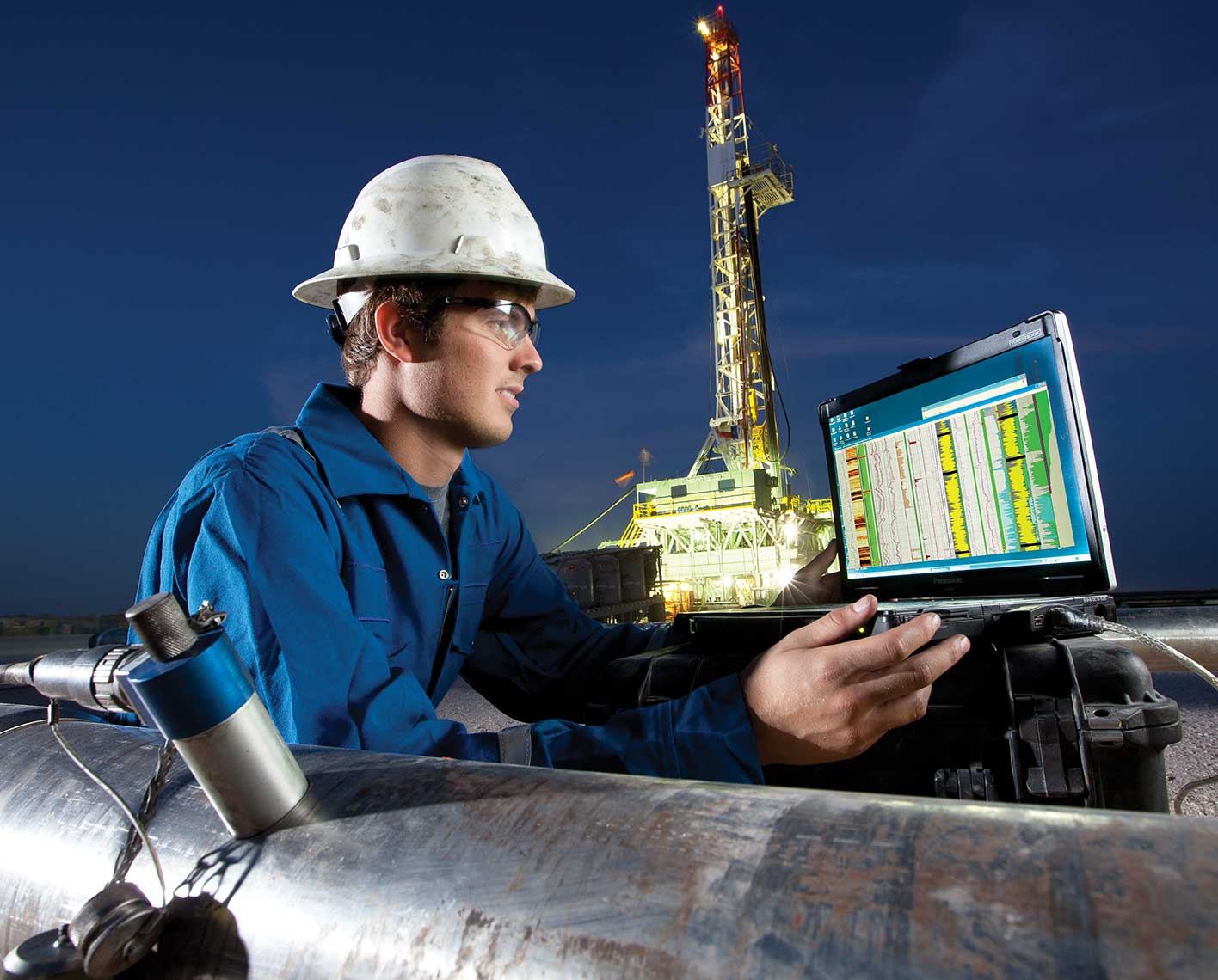 SLB technician configuring an LWD tool on a drilling pad at night.