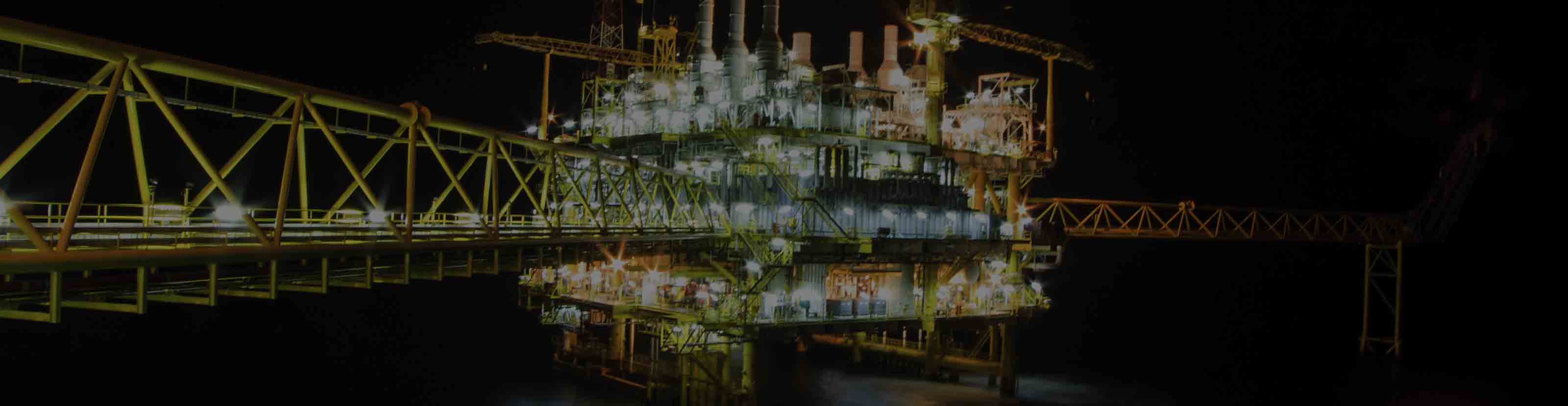 A brightly lit offshore drilling and production platform at night