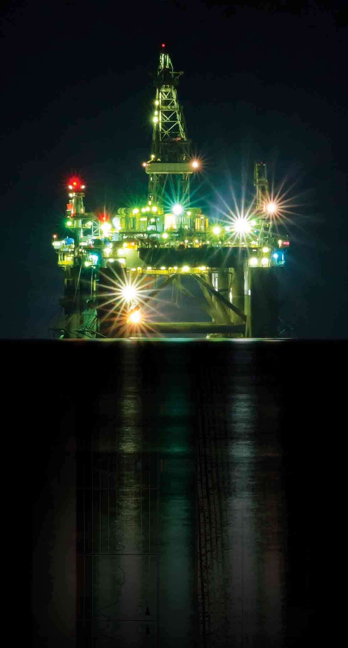 A deepwater rig at night whose reflection has been replaced with an LWD log from the SpectraSphere fluid mapping-while-drilling service