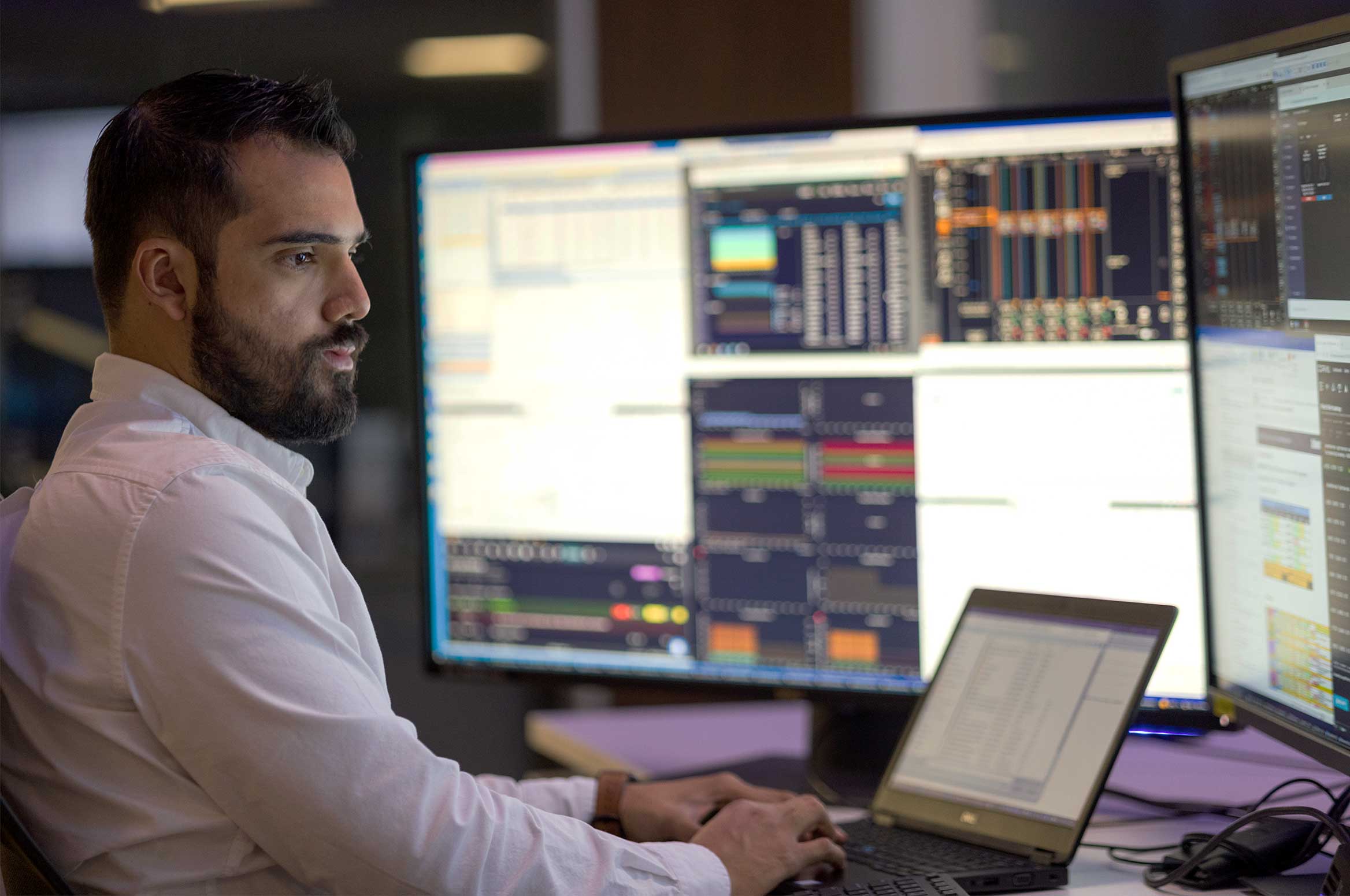Engineer working on many screens at a desk in the Performance Live service center.