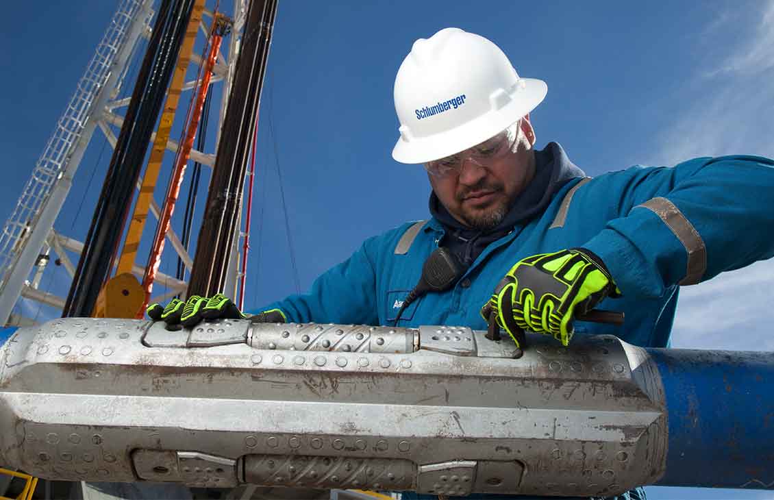 Schlumberger worker performing maintenance on an OnGauge torque-reduction sealed-bearing roller reamer.