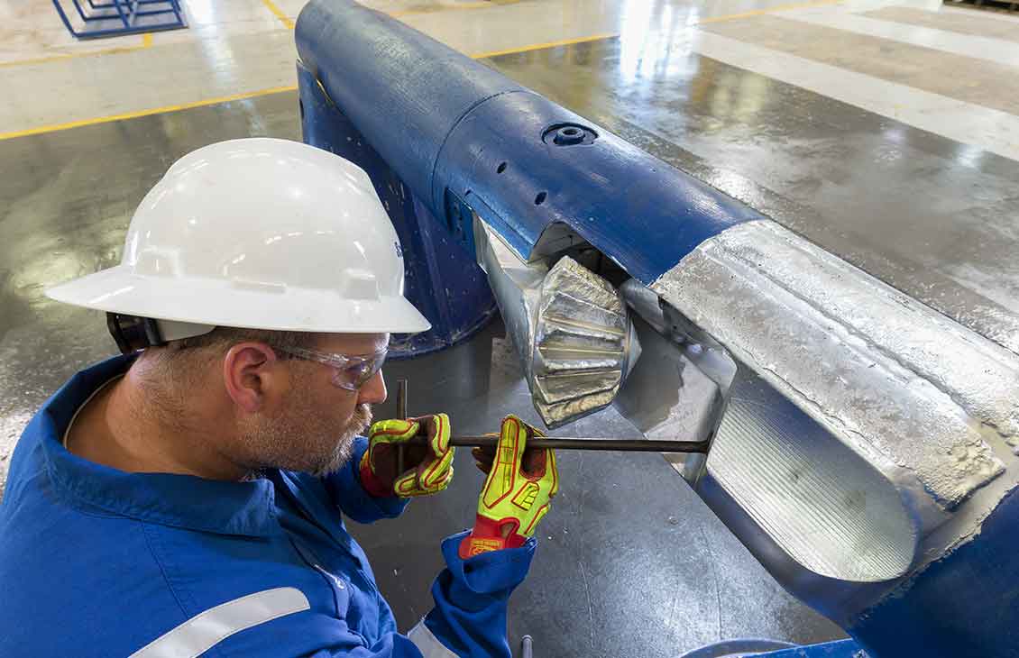 Schlumberger worker performing maintenance on a Reamaster-XTU forged cutter arm underreamer.