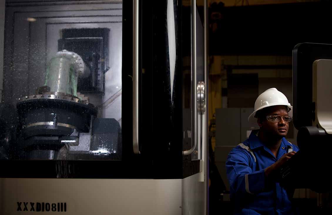 Schlumberger worker reviewing data on monitor while performing testing on reamers and stabilizers.