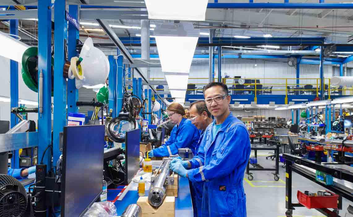 People in workshop working on downhole logging equipment