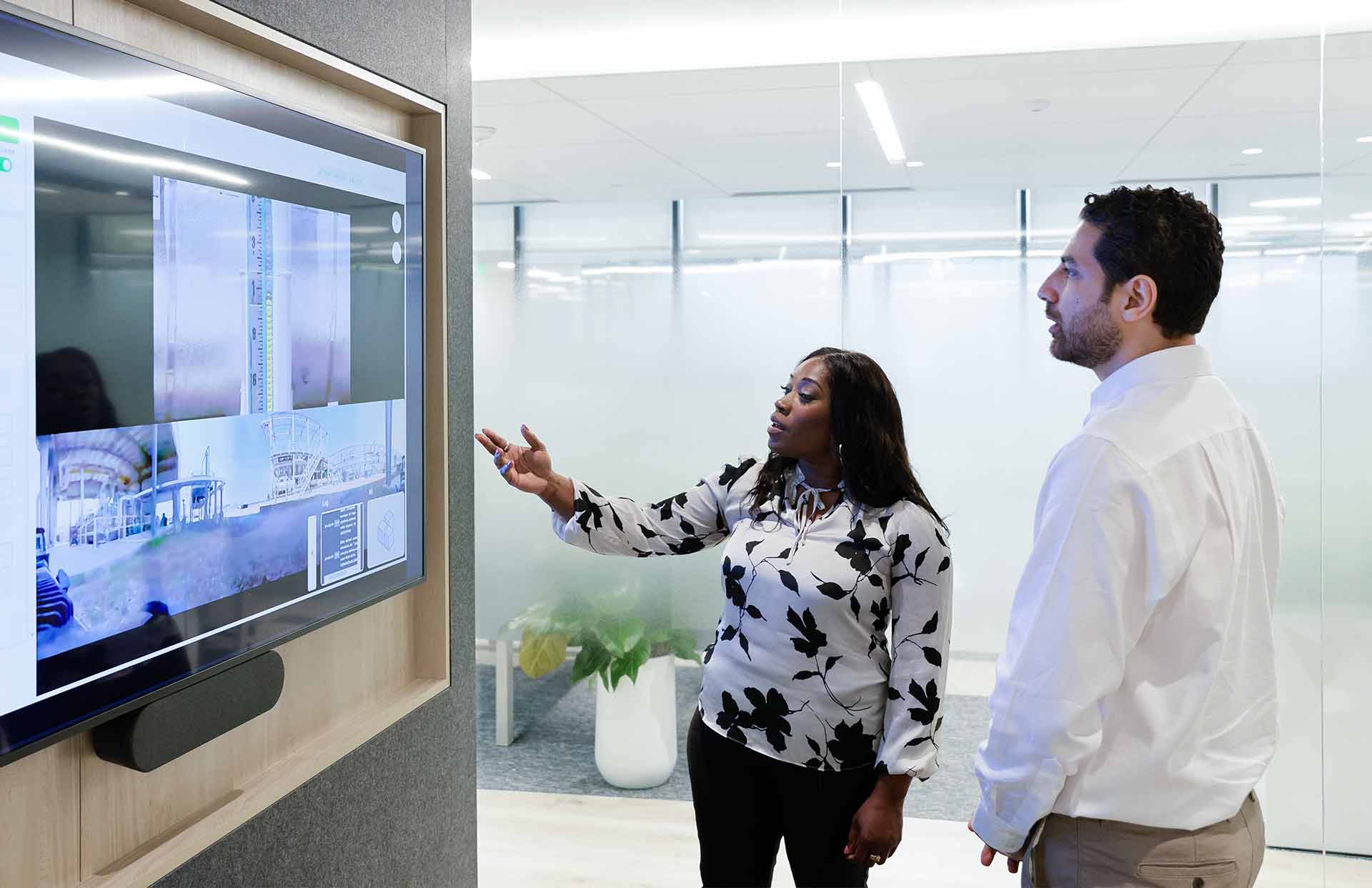 Two SLB employees discussing a large display in a Performance Live digital service delivery center.
