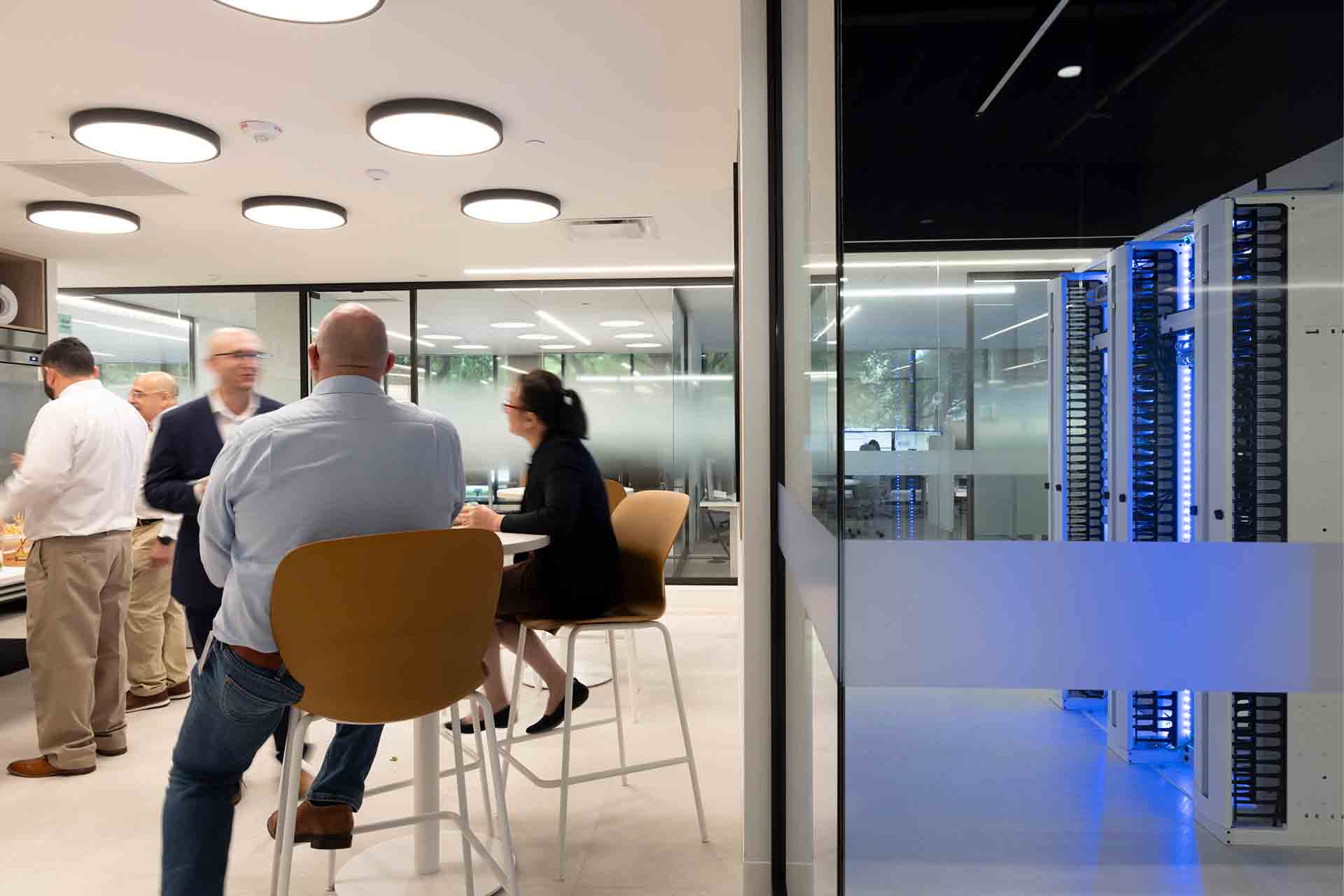 Photo of people discussing and a server behind glass walls at a Performance Live center.