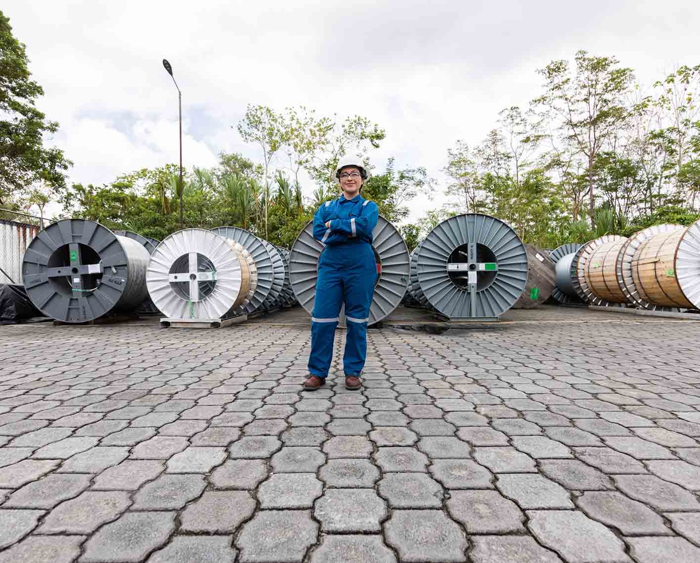 Operator in SLB blue coveralls standing in front of spools of equipment