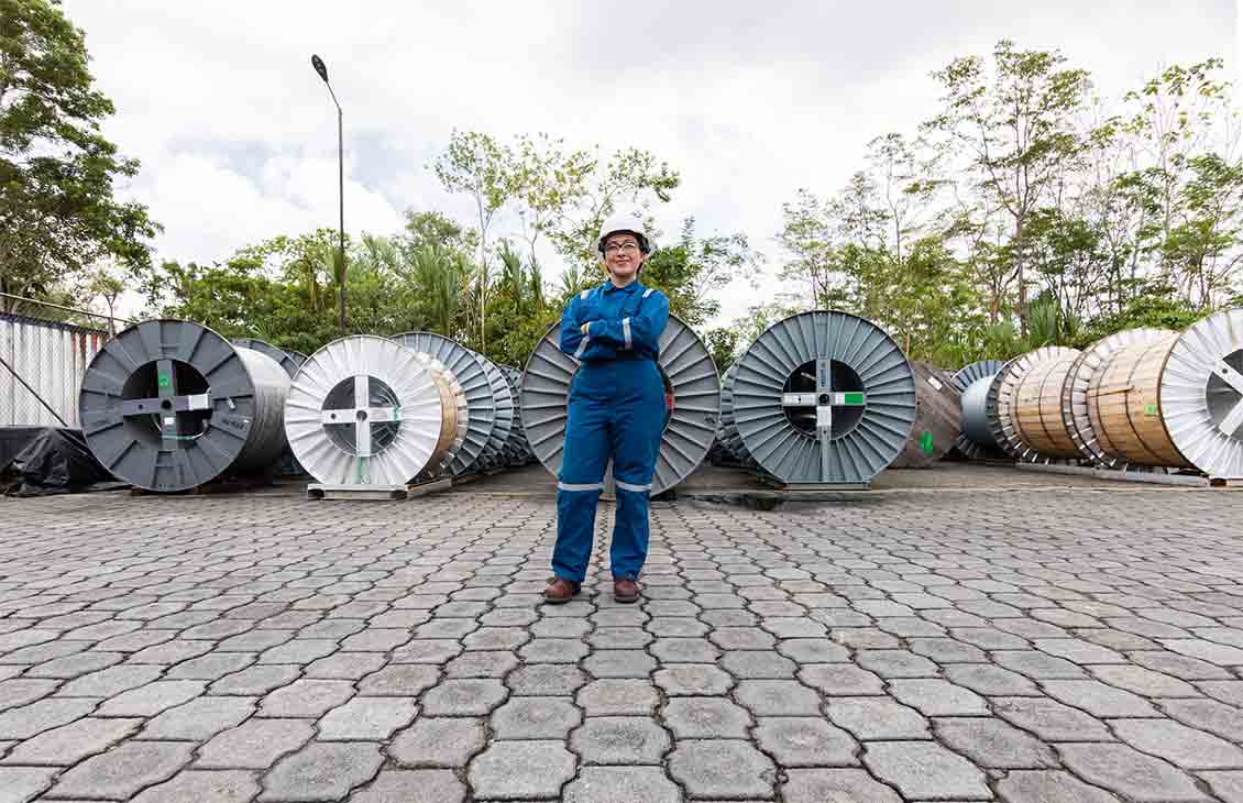 Operator in SLB blue coveralls standing in front of spools of equipment