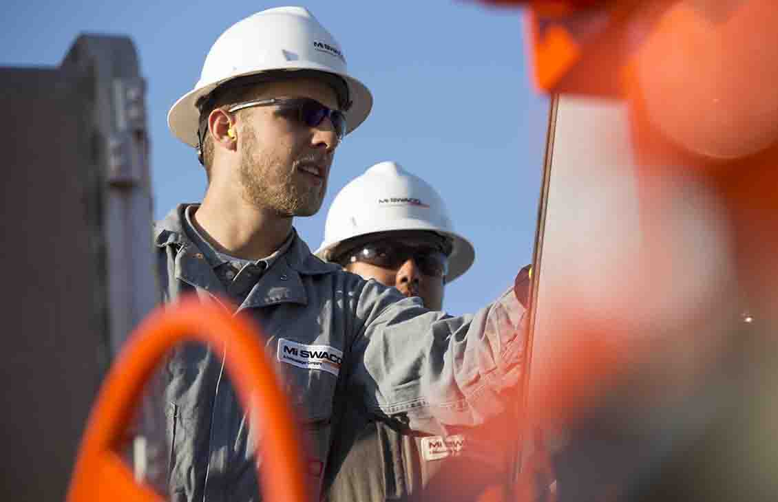 People in PPE next to orange equipment.