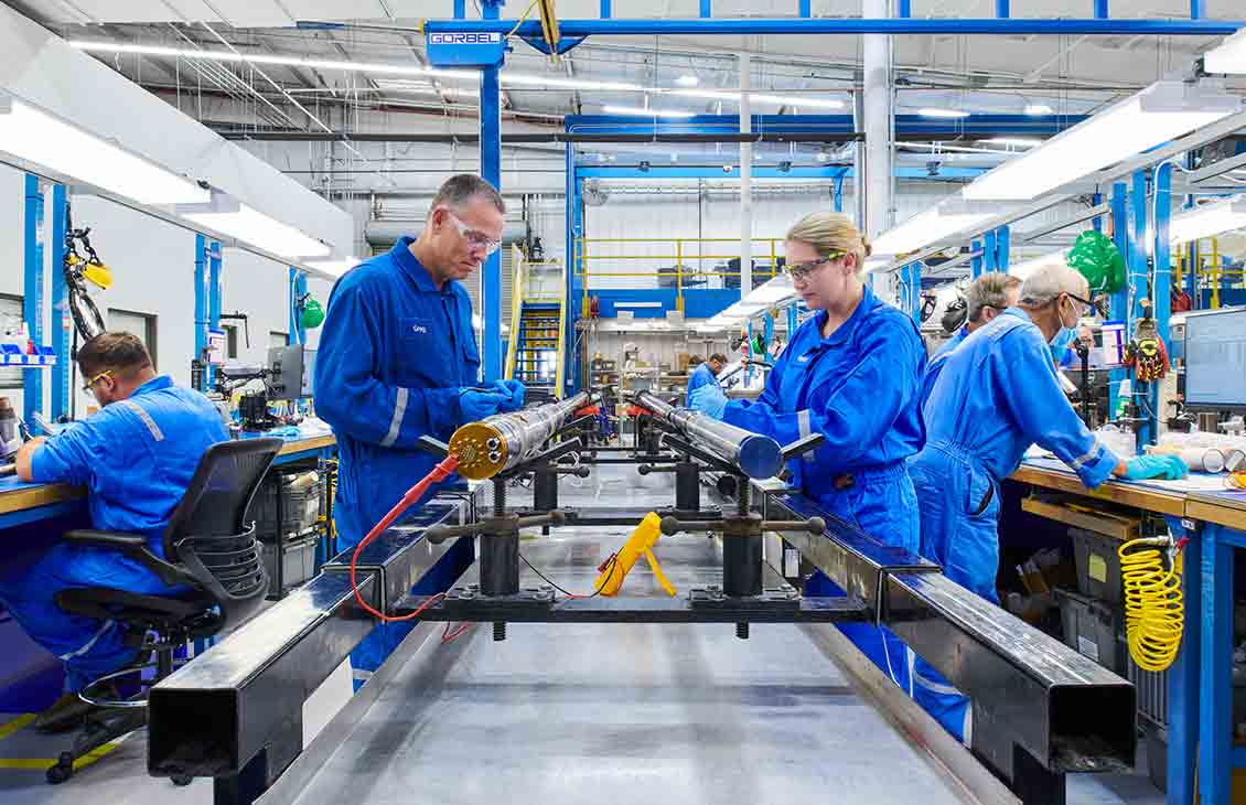 Photo of man and woman in blue coveralls working on abandonment tools in a manufacturing facility (Tier 1_ManufacturingFacility_Sugar Land_AML_5251)