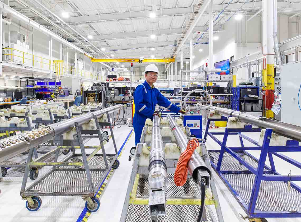 Photo of man in blue overalls working on abandonment tools in a manufacturing facility (Tier 1_ManufacturingFacility_Sugar Land_AML_5396)