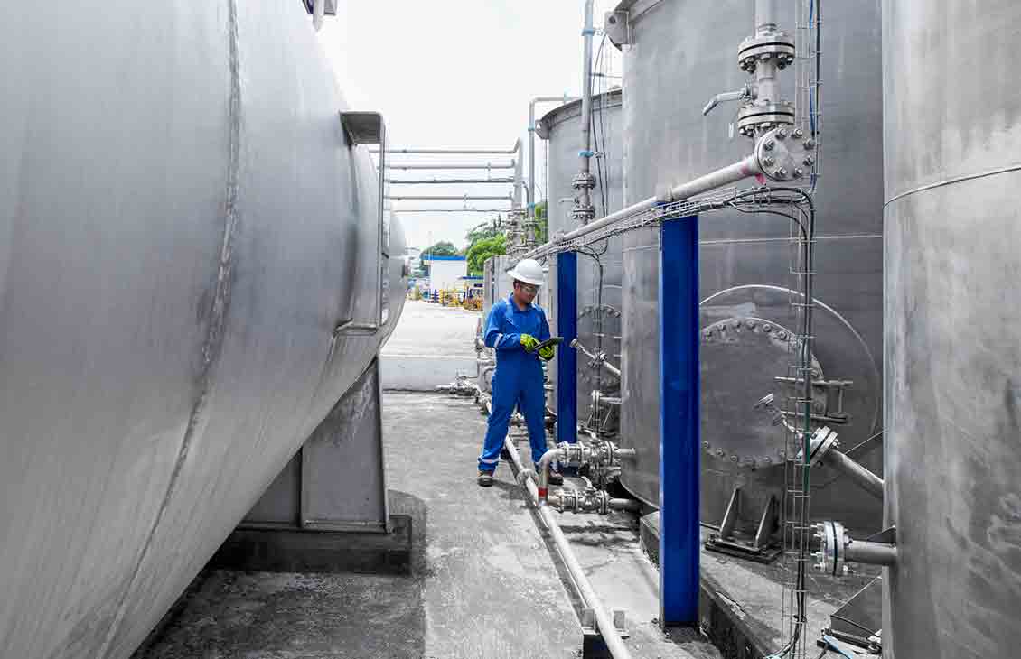 Photo of an in blue coveralls monitoring tanks (Tier 1_ManufacturingFacility_Singapore_ASIA_15896)