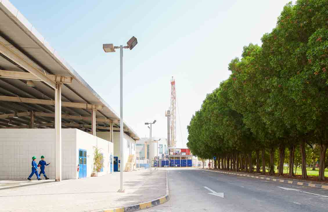 Photo of people walking outside, rig in background at the end of the street
