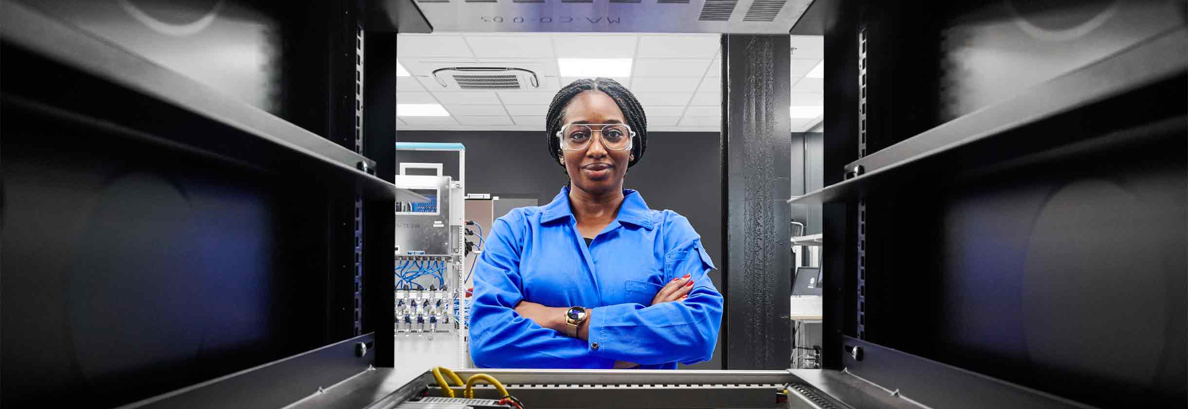 A woman in SLB blue coveralls looking through a metal shelf