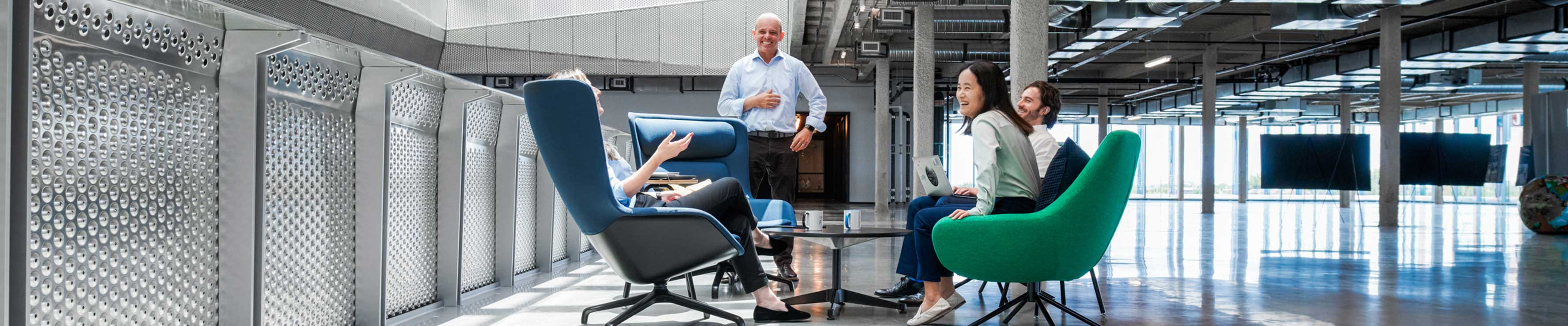 Two men and two women sitting in chairs around a table having a meeting