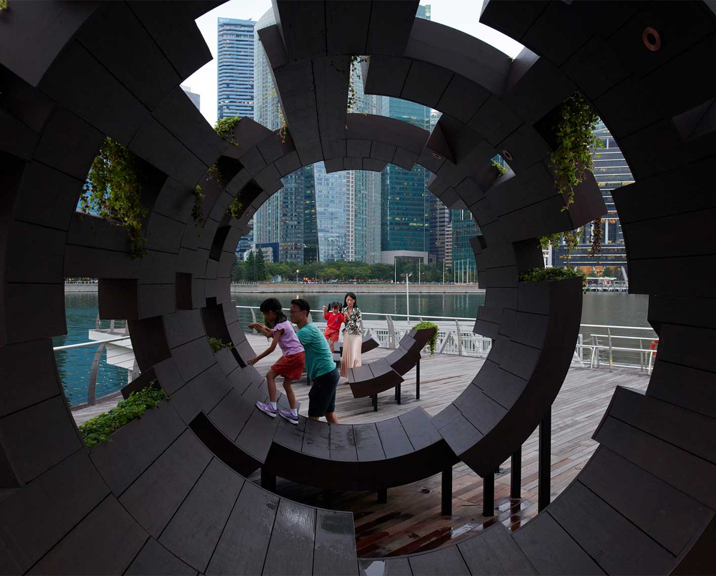 a family and children playing outside on a tubular architectural piece