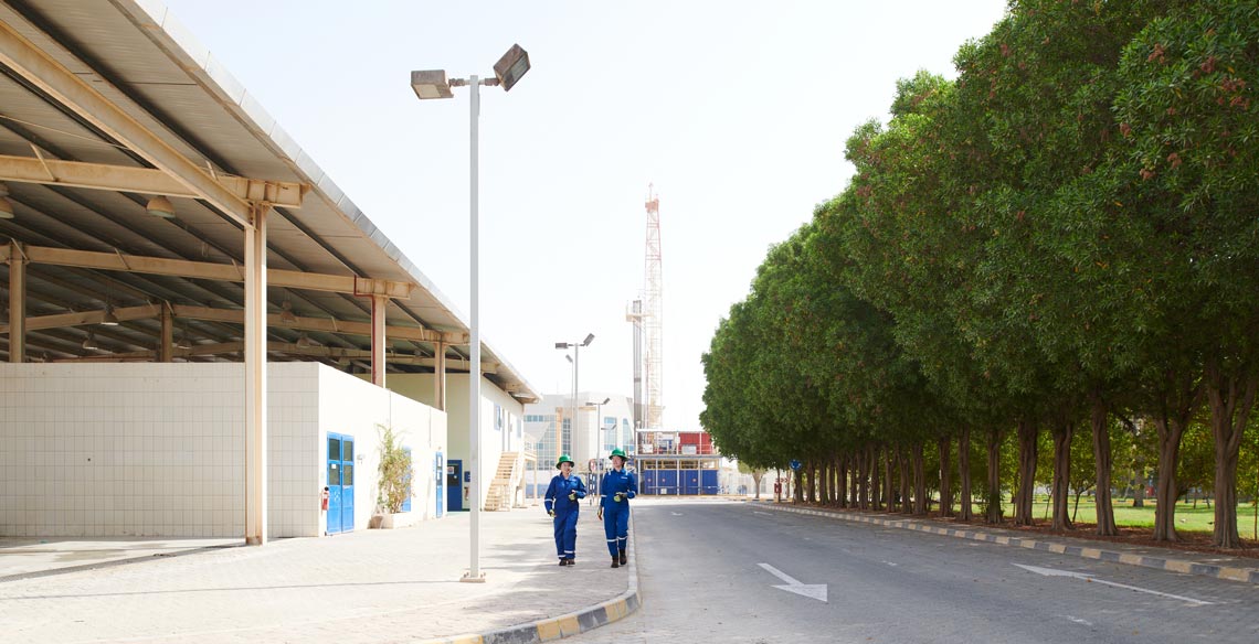 Two operators walking down the street with a land rig in the distance