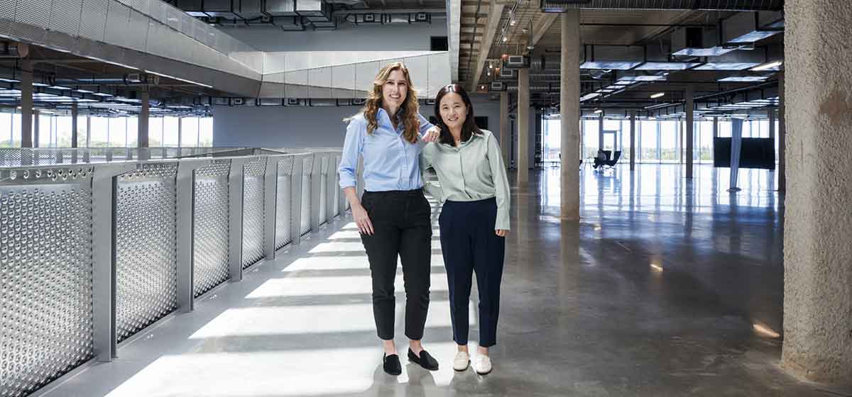 Two women standing in office building hallway