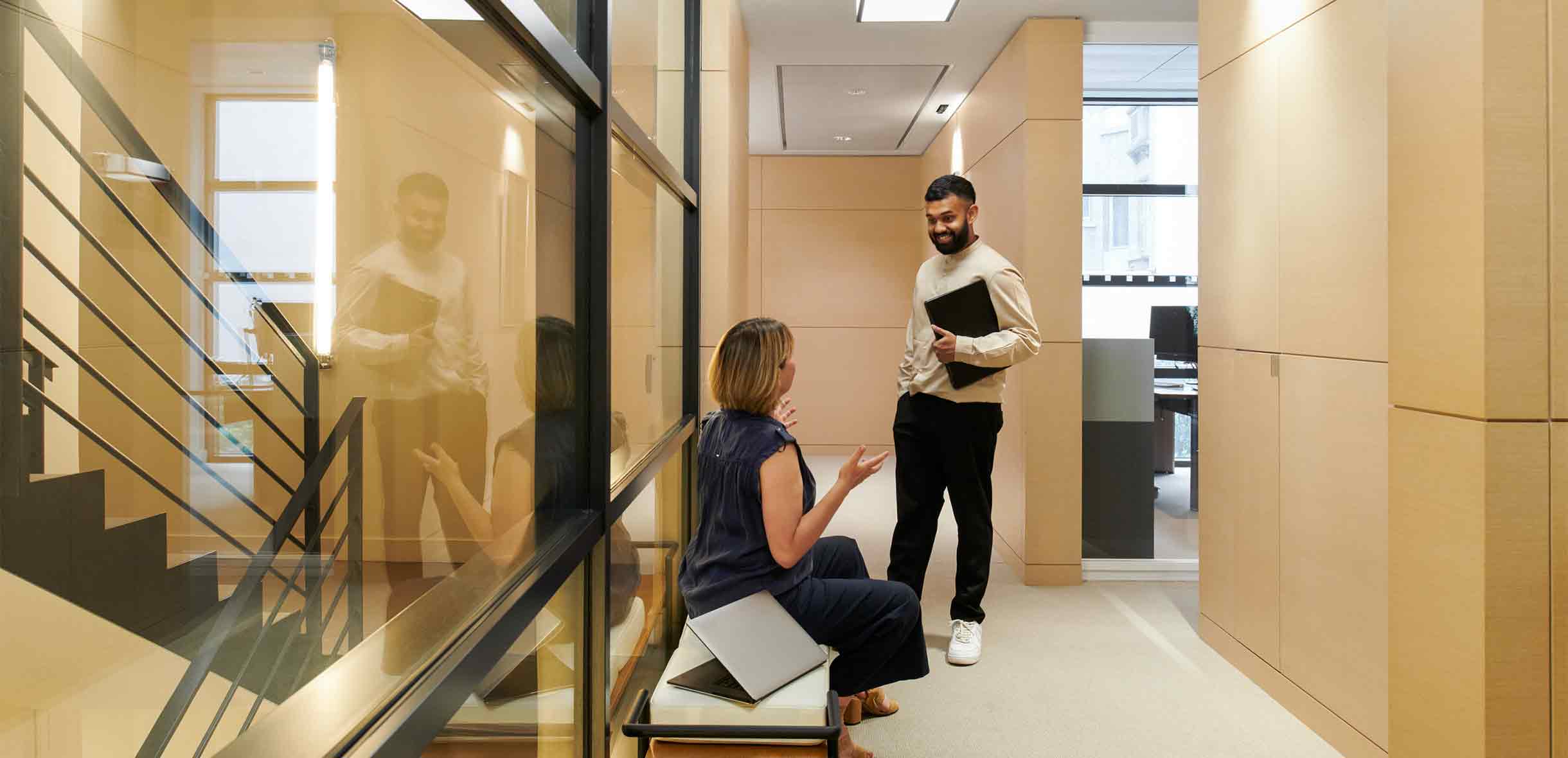 two people having a conversation in an office hallway