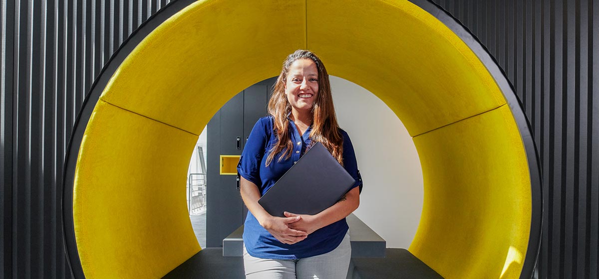 Women holding laptop in front of a big circle yellow structure (Tier 1_Office_Clamart_OAT_0350)