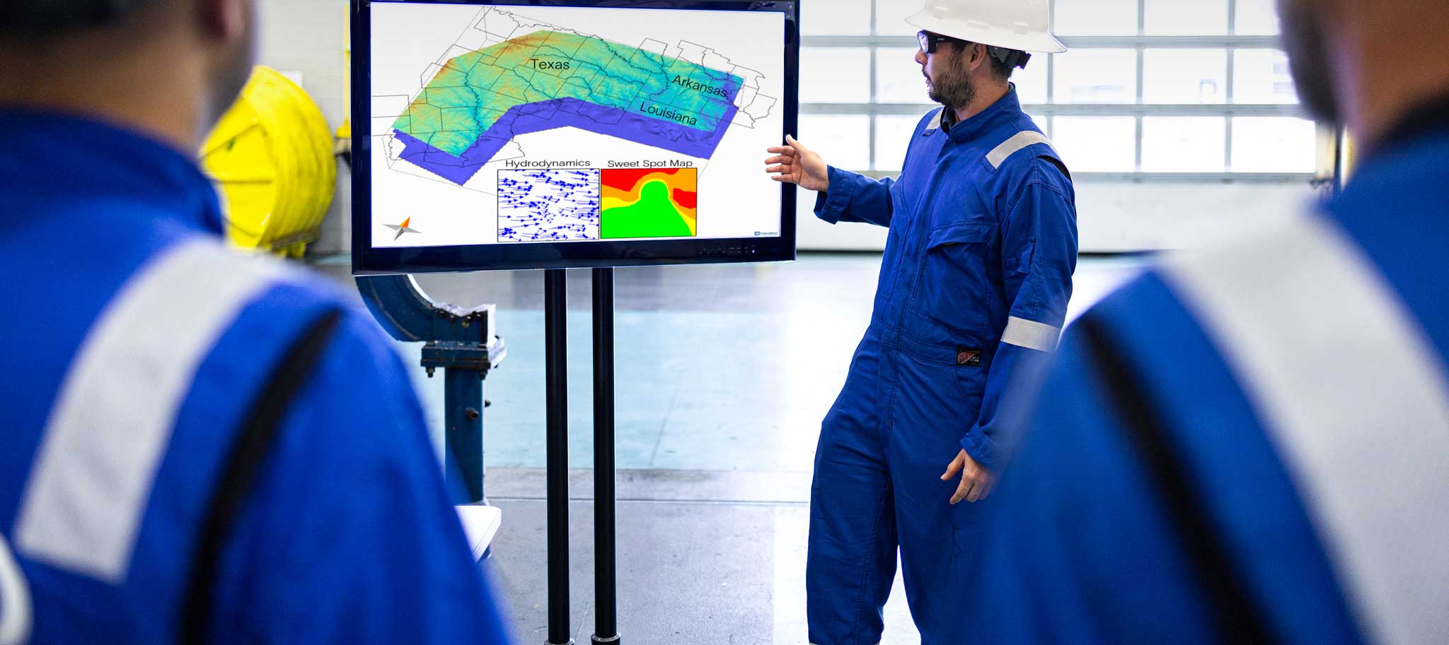 Worker in hard hat presenting subsurface map of Texas, Louisiana, and Arkansas on screen.