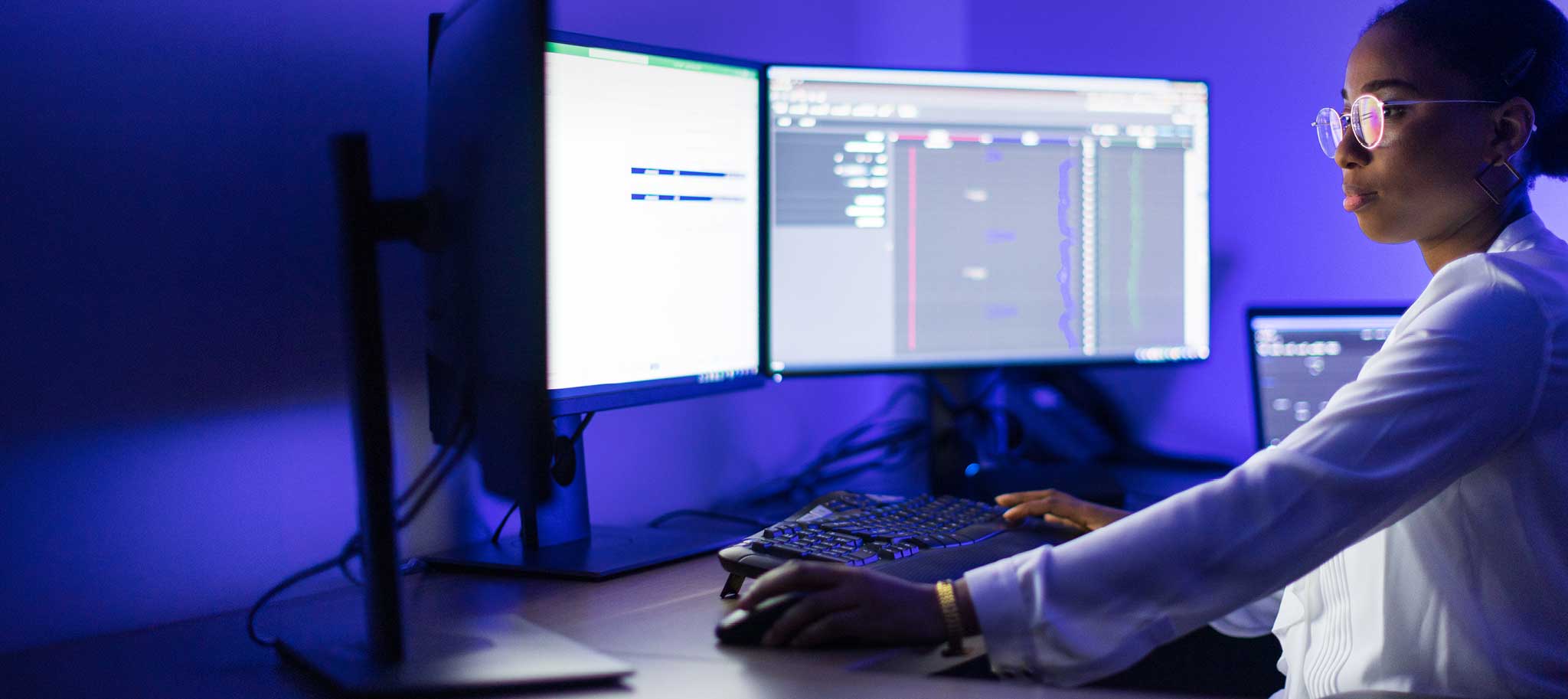 Woman in room looking at 2 computer screens