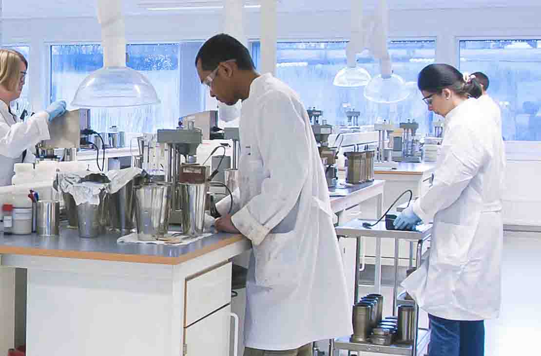 Three people in lab coats in a fluids laboratory.