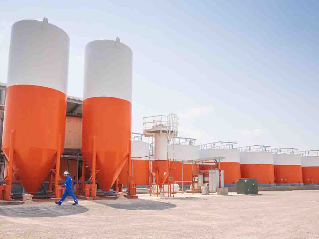 Employee in blue jumpsuit walking past orange hoppers.