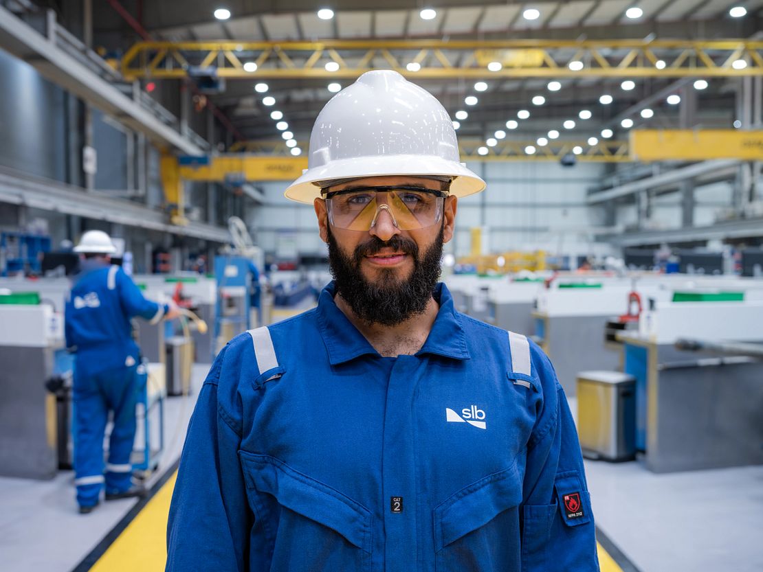 Worker in blue safety gear inside a bright industrial facility.