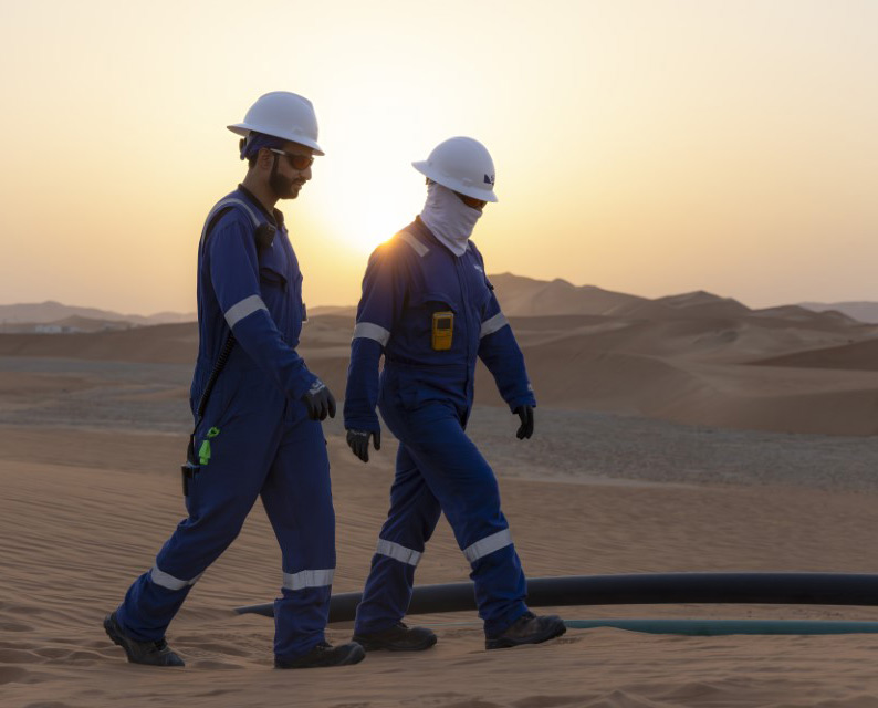 2 SLB employees walking in the sand